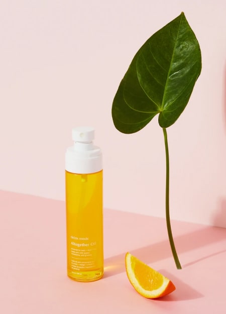 Żółta butelka z kawałkiem pomarańczy i stojącym liściem.